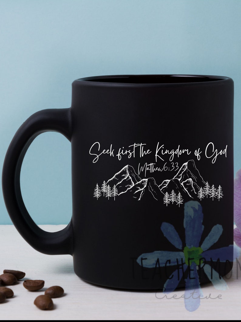 May include: Black ceramic coffee mug with a white design of mountains and trees. The text "Seek first the Kingdom of God" and "Matthew 6:33" is printed on the mug.