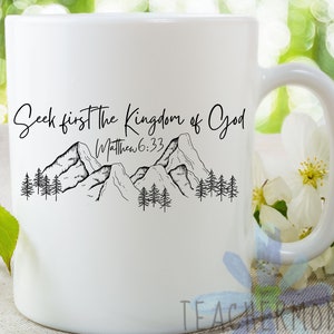 May include: White ceramic mug with a black design of mountains and trees. The text "Seek first the Kingdom of God" and "Matthew 6:33" is printed on the mug.