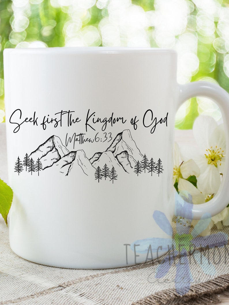 May include: White ceramic mug with a black design of mountains and trees. The text "Seek first the Kingdom of God" and "Matthew 6:33" is printed on the mug.