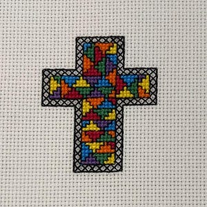 Peut inclure: Un motif de point de croix coloré représentant une croix avec un motif en mosaïque dans des tons de rouge, orange, jaune, vert, bleu et violet.