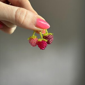 May include: A cluster of three small berry charms crafted from tiny glass beads in shades of light pink, vibrant magenta, and deep maroon. Each berry features a small green beaded stem and leaf detail, connected together by a small metal jump ring.