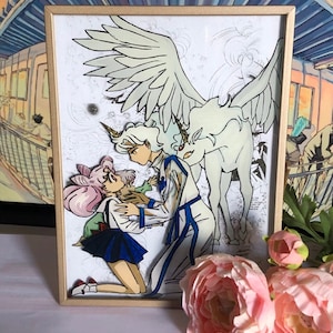 Könnte beinhalten: Eine gerahmte Illustration eines weißen geflügelten Einhorns mit einer Frau in einem blauen Kleid und einem Mann in einem weißen Hemd und einer Hose. Die Frau kniet und der Mann steht mit dem Arm um sie herum. Die Illustration ist in einem goldenen Rahmen.