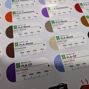 Puede incluir: Una hoja de pegatinas ovaladas blancas para bobinas de filamento de impresora 3D. Cada etiqueta incluye una secci&oacute;n de color, el logotipo de Bambu Lab, el tipo de material, el nombre del color, rangos de temperatura y una escala de peso.