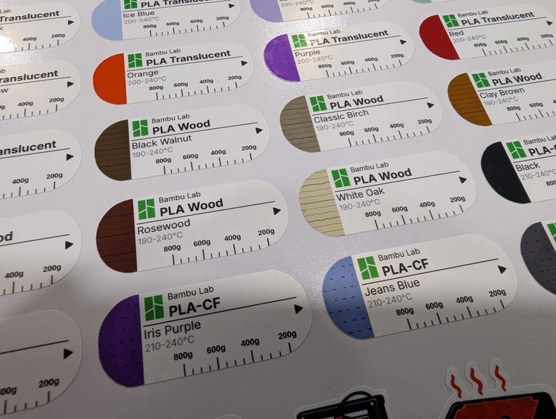 Puede incluir: Una hoja de pegatinas ovaladas blancas para bobinas de filamento de impresora 3D. Cada etiqueta incluye una secci&oacute;n de color, el logotipo de Bambu Lab, el tipo de material, el nombre del color, rangos de temperatura y una escala de peso.