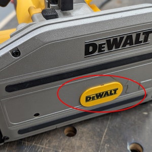 Puede incluir: Primer plano de una sierra de riel DeWalt. La sierra es principalmente gris y amarilla, con el logotipo de DeWalt en negro y amarillo. La sierra parece nueva y en buen estado.