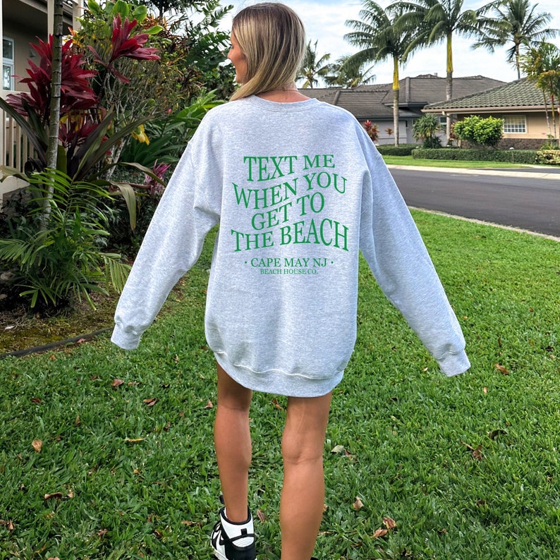 May include: Gray sweatshirt with green text that reads "Text me when you get to the beach. Cape May NJ. Beach House Co."