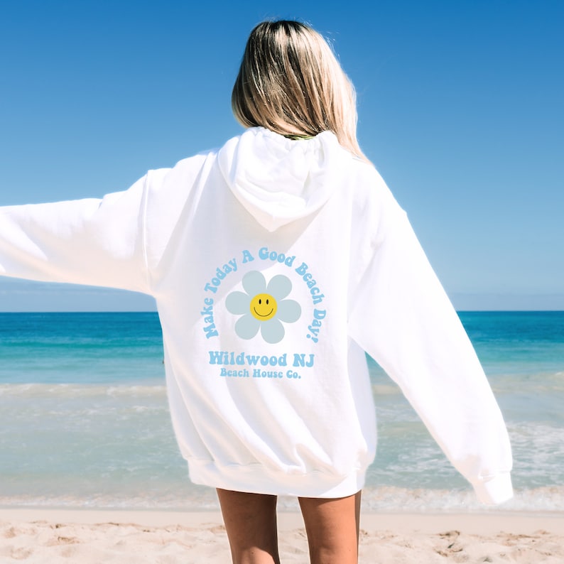 K&ouml;nnte beinhalten: Wei&szlig;er Hoodie mit einem blauen und gelben Blumenmotiv auf der R&uuml;ckseite. Der Aufdruck lautet "Make Today A Good Beach Day!" und "Wildwood NJ Beach House Co."