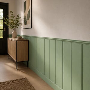 May include: A hallway interior featuring sage green vertical board and batten wainscoting on the lower half of the wall. A light wood sideboard with a slatted front stands against the wall, topped with a ceramic vase containing green foliage.