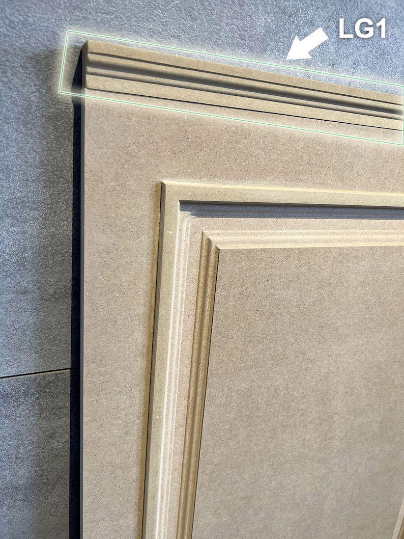 May include: A light brown wooden cabinet door with a raised panel design. The door has a decorative trim around the edge, labeled "LG1".