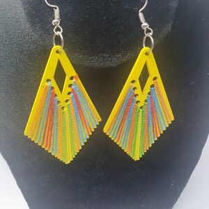 May include: A pair of yellow diamond-shaped earrings with colorful thread fringe. The earrings have silver hooks.