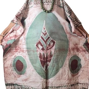 May include: A flowing, patterned dress in shades of white, teal, and maroon. The dress features an oval design with a central diamond shape and circular accents. The fabric has a batik-like appearance, with a loose, comfortable fit.