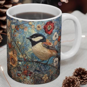 May include: White ceramic mug with a colorful design featuring a bird perched on a branch with flowers and berries. The bird is brown, black, and white with a blue background.