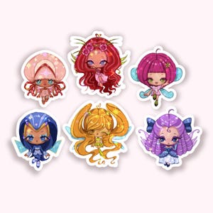 Puede incluir: Una colección de seis pegatinas de hadas coloridas. Cada pegatina presenta un diseño de hada único con diferentes peinados, atuendos y accesorios. Las hadas tienen ojos grandes y están sobre un fondo blanco.