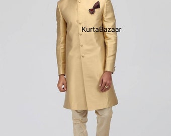 May include: A gold-colored, long-sleeved sherwani suit with a mandarin collar and a decorative pocket square. The outfit includes matching beige pants and embroidered shoes. The text "KurtaBazaar" is visible on the garment.