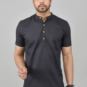 May include: A black short-sleeved collared shirt with a button placket and a single pocket on the left chest. The shirt has a mandarin collar and is made of a lightweight fabric.