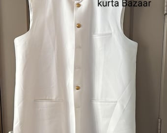 May include: A sleeveless white vest with a mandarin collar and gold-colored buttons. The vest has two front pockets and is hanging on a black hanger. The text "kurta Bazaar" is visible on the right side of the vest.