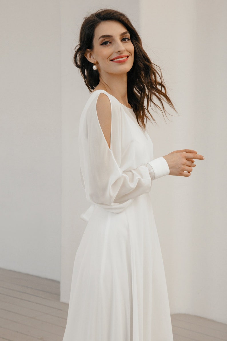 Long sleeve chiffon wedding dress with open back, soft boat neckline, and airy skirt