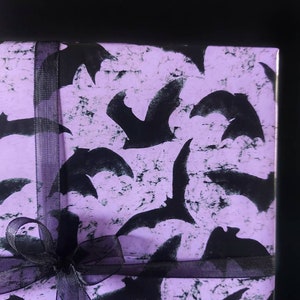 May include: Purple gift wrap with a black ribbon and a pattern of black bats.