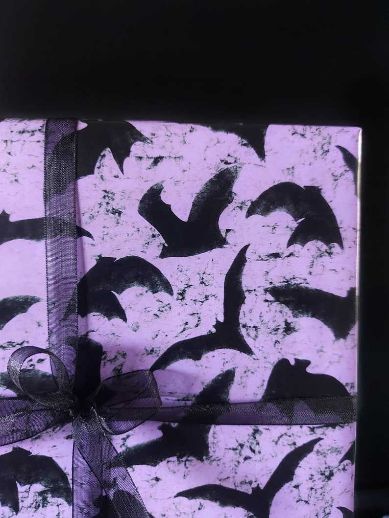 May include: Purple gift wrap with a black ribbon and a pattern of black bats.