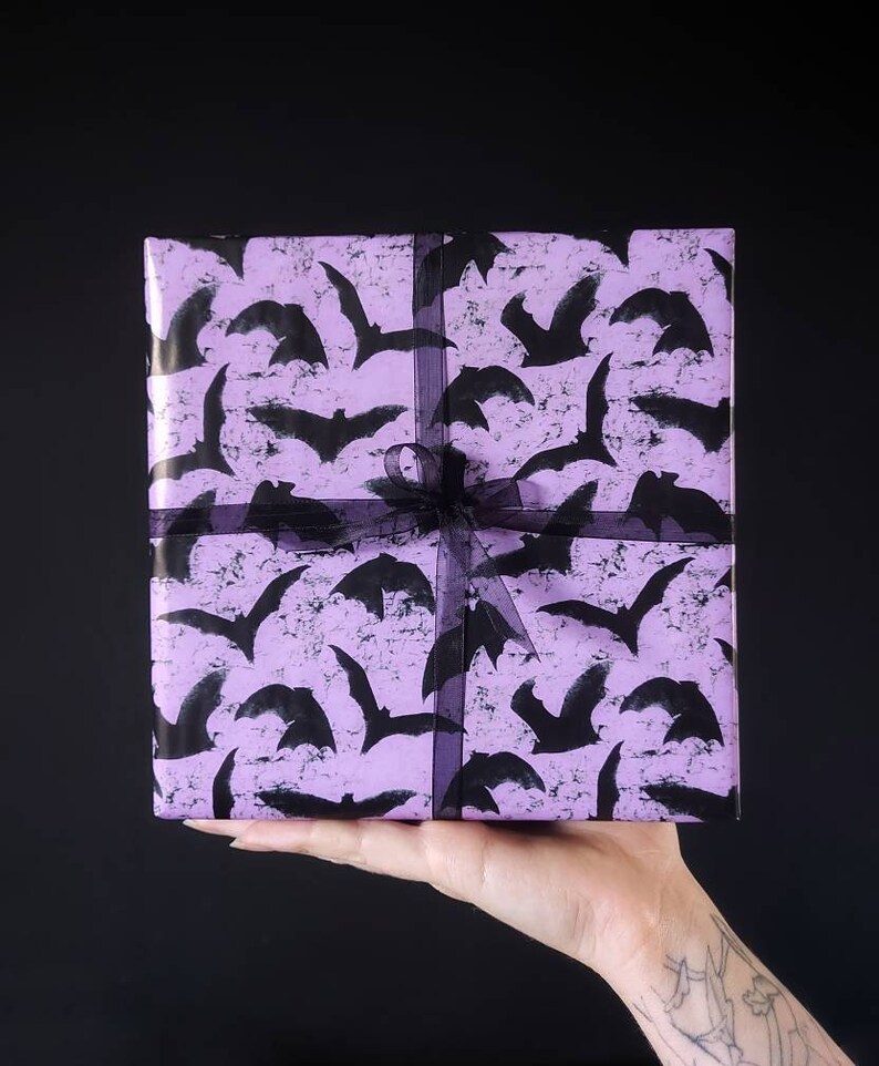May include: A purple gift box with a black bat pattern and a black ribbon.