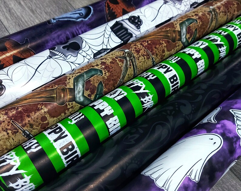 May include: Five rolls of Halloween themed wrapping paper. The designs include a skull and spider web, a rusty tool, a green and black striped pattern with the text "Happy Birthday", a black and white floral pattern, and a purple and white pattern with a ghost.