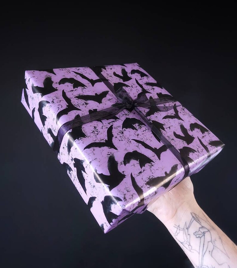 May include: A purple gift box with a black bat pattern and a black ribbon.