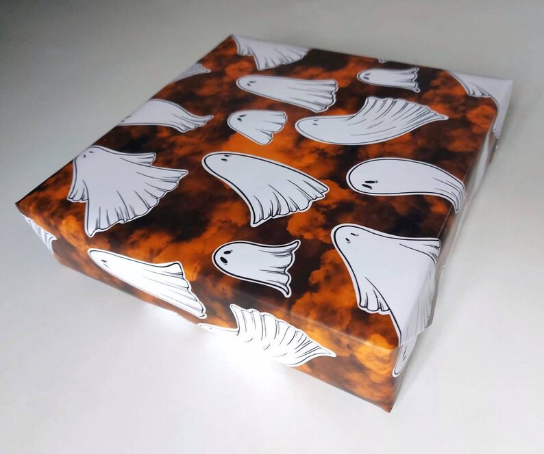 May include: Orange and black wrapping paper with a pattern of white ghosts. The ghosts are in various sizes and positions.