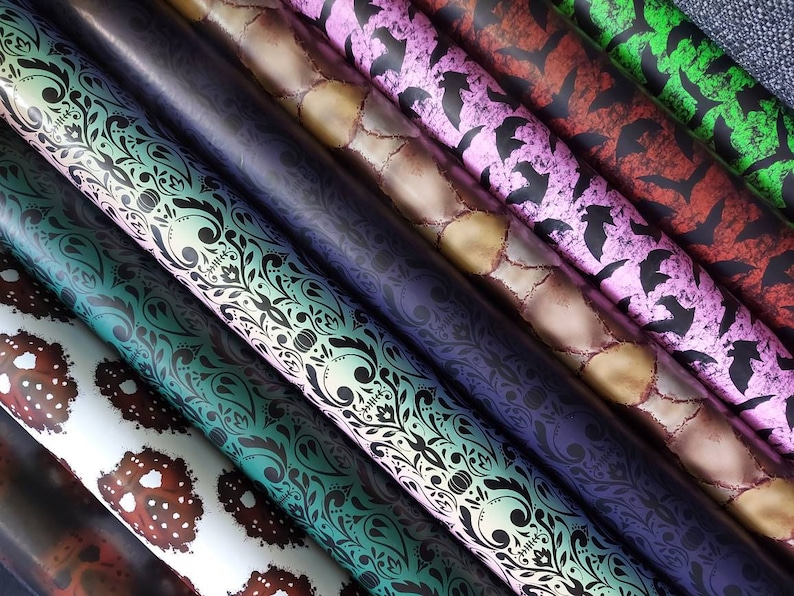 May include: A collection of patterned wrapping paper rolls, featuring designs like skulls, bats, and floral patterns. The rolls are arranged in a fan shape, showcasing the different designs.