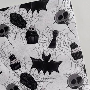 Peut inclure: Papier d'emballage sur le th&egrave;me d'Halloween noir et blanc avec un motif r&eacute;p&eacute;t&eacute; de cupcakes, de chauves-souris, de cercueils et de cr&acirc;nes. Le fond est un motif de toile d'araign&eacute;e blanche.