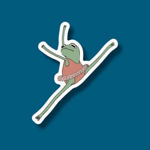May include: A green frog wearing a pink tutu and performing a ballet pose. The frog has a surprised expression on its face.