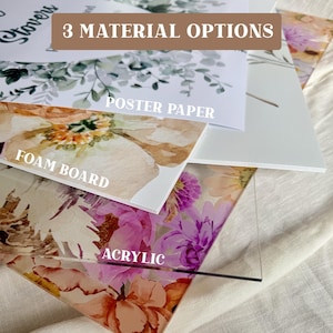 May include: An image showcasing three material options: poster paper, foam board, and acrylic. Each material displays a floral design with a variety of colors, including pink, orange, and green. The text "3 MATERIAL OPTIONS" is visible at the top.