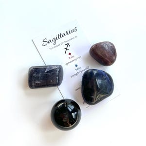 May include: Sagittarius zodiac sign crystal set with a card that says "Sagittarius, November 22 - December 21" and lists the crystals: Ruby, Kyanite, and Black Tourmaline.