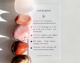 May include: A set of five tumbled stones, including pink opal, rhodonite, red jasper, and mangano calcite, with a card that reads "I AM WORTHY" and descriptions of the stones' properties.