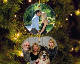 May include: A personalized Christmas ornament featuring two family photos. One photo shows a couple, and the other shows a family with a dog. The ornament is round with a gold string for hanging. The text "1 Day Shipping!" is at the top.