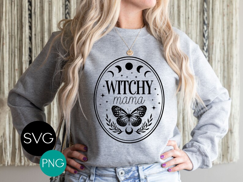 K&ouml;nnte beinhalten: Ein graues Sweatshirt mit einem schwarzen Aufdruck, der "Witchy Mama" in einem ovalen Rahmen mit Mondphasen, Sternen, einem Schmetterling und Bl&auml;ttern zeigt. Das Bild enth&auml;lt auch die Texte "SVG" und "PNG" in einem Kreis.