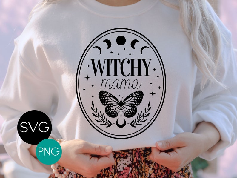K&ouml;nnte beinhalten: Wei&szlig;es Sweatshirt mit einem schwarzen Grafikdesign. Das Design zeigt die Worte "Witchy Mama" in einem ovalen Rahmen, einen Schmetterling, Halbmonde und Sterne. Das Bild enth&auml;lt auch die Texte "SVG" und "PNG" in einem schwarzen und t&uuml;rkisfarbenen Kreis.
