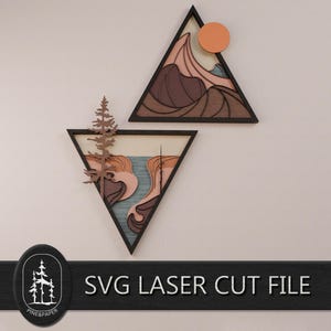 May include: Two triangular wall art pieces featuring layered wood designs. The top triangle shows mountains and a sun in shades of brown, tan, and orange. The bottom triangle depicts a river, landscape, and a pine tree. Text reads SVG LASER CUT FILE.