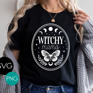 K&ouml;nnte beinhalten: Schwarzes T-Shirt mit wei&szlig;em Oval-Design, das den Text "Witchy mama" enth&auml;lt, zusammen mit Monden, Sternen und einem Schmetterling. SVG- und PNG-Logos sind ebenfalls abgebildet.