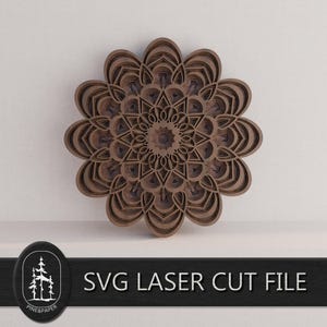 Może przedstawiać: Wielowarstwowa drewniana mandala w odcieniach brązu, z szczegółowym kwiatowym wzorem. Grafika jest zamontowana na białej ścianie. Tekst "SVG LASER CUT FILE" jest wyświetlany pod mandalą.