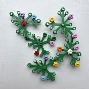 May include: Green plastic floral-shaped craft pieces with colourful flower accents in red, purple, blue, yellow, orange, and white. The pieces have a snowflake-like design with circular connection points.