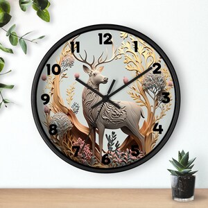 May include: A black framed clock with a white deer and floral design. The clock face has black Roman numeral hour markers and black hands.