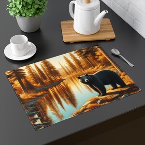May include: A black bear stands on a rock by a lake in a forest setting. The lake reflects the trees and the sky. The scene is depicted in a realistic style with warm colors.