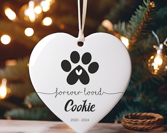 May include: White ceramic heart-shaped ornament with a black paw print and the text "forever loved Cookie 2020-2024".