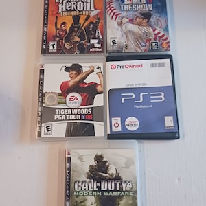 May include: Five PlayStation 3 video game cases. The cases are arranged in a row from left to right. The games are Guitar Hero III: Legends of Rock, Tiger Woods PGA Tour 08, MLB 11 The Show, Call of Duty 4: Modern Warfare, and a pre-owned game case.