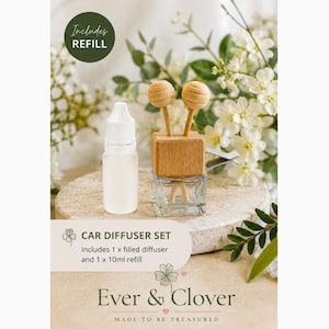 May include: A car diffuser set featuring a clear glass bottle with a wooden top, two wooden sticks, and a 10ml refill bottle. The text reads: Includes REFILL, CAR DIFFUSER SET, Includes 1 x filled diffuser and 1 x 10ml refill, Ever & Clover, MADE TO BE TREASURED.