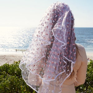 May include: A white bridal veil with a white satin trim and pink and white glitter hearts and other shapes.