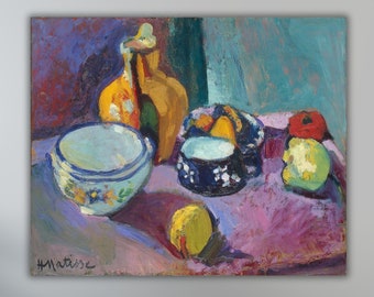 Può includere: Una natura morta del pittore Henri Matisse che rappresenta una brocca di ceramica gialla, tre ciotole blu e bianche, una mela gialla e una mela rossa su una tovaglia viola.