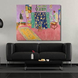 May include: A painting depicting a room with a pink floor, a blue rug, and a blue curtain with floral designs. There are several figures in the room, including a nude figure standing on a platform, a figure sitting on a stool, and a figure standing near a table. The painting is framed and hanging on a wall.