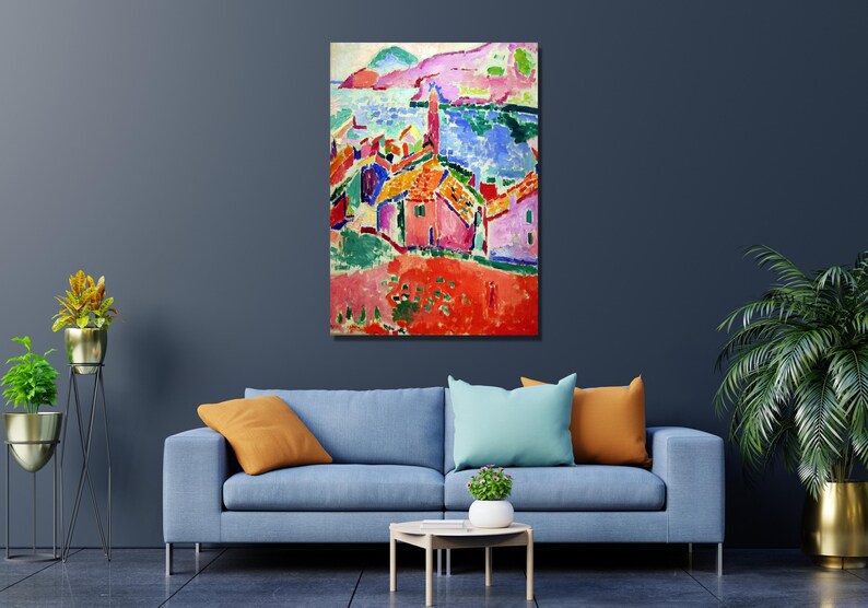 May include: A colorful abstract painting of a seaside village with houses in shades of pink, red, yellow, and blue. The painting features a bright blue sea and a green hillside in the background.