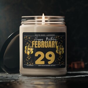 May include: A white soy candle with a black label that says "Happy Birthday!! February 29" with gold confetti and balloons. The candle is eco-friendly, 100% vegan, and made with natural soy wax.